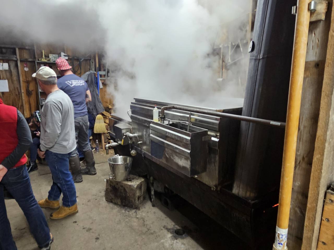 Steam rising from the maple evaporator as people gather inside the Knolltop Farm sugarhouse